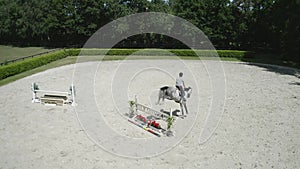 Horse Jumping over obstacle. Followed by a drone. Aerial Shot. Young Man Rider. Horseback