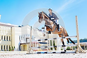 Horse man wearing blue jacket feeling excited while horse hurdling