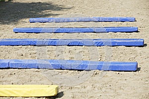 Horse obstacle course outdoors summertime. Poles in the sand at equestrian center outdoors