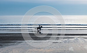 Horse Rider Galopping At Newgale Beach At The Atlantic Coast Of Pembrokeshire In Wales, United Kingdom