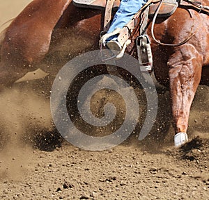 A horse and rider moving fast with dirt flying.