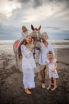 Horse riding on the beach. Little pretty girl on a horse. Mother stroking a horse. Father hugging daughter. Family concept. Summer