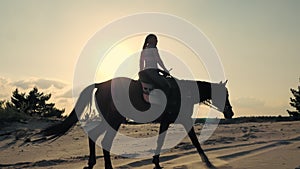 Horse riding. Silhouette of rider and horse. horsewoman is riding a horse on sandy ground, at sunset, against sun