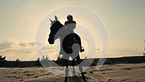 Horse riding. Silhouette of rider and horse. horsewoman is riding a horse on sandy ground, at sunset, against sun