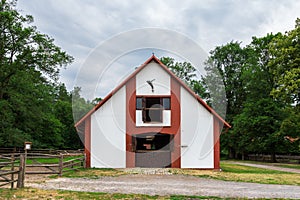 Horse stud in Florianka. White and red wooden panels on the facade. A paddock for horses