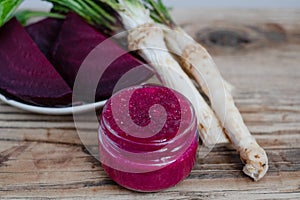 Horseradish and beetroot saucer in a small glass on a rustic wooden table.