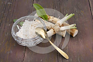 Horseradish grated in glassware and roots