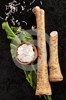 Horseradish root and grated horseradish on black background.