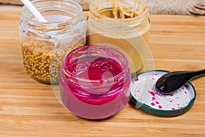 Horseradish sauce with beetroot in jar against of various mustard