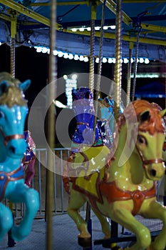 Horses on carousel merry go round at carnival in nighttime