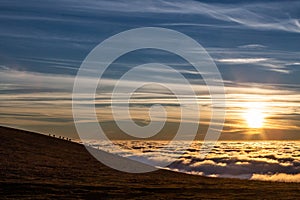 Horses silhouettes on a mountain over a sea of fog at sunset, with beautiful warm colors