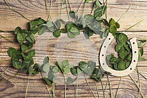 Horseshoe with clover leaf frame on old wooden boards. St. Patricks day, lucky charms
