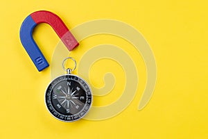 Horseshoe magnet with blue and red with compass on vivid yellow background with copy space using for special force or charm,