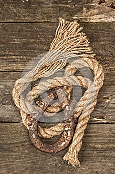 Horseshoe and vintage rope. Concept of good luck for St. Patrick`s Day. Old wooden boards background