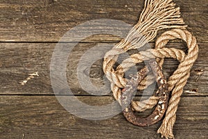 Horseshoe and vintage rope. Concept of good luck for St. Patrick`s Day. Old wooden boards background
