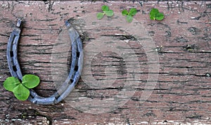 Horseshoe on a wooden background with a leaf of clover on St. Patrick`s day