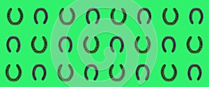 Horseshoes black on green background pattern, symbol of good luck