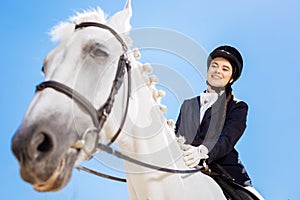 Horsewoman wearing white gloves sitting on her white horse