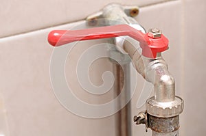 A hose plug quarter turn lever type ball valve water tap with red handle.