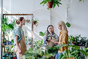 Hospitable Caucasian male and Asian female business owners chatting with a customer in a flower store.