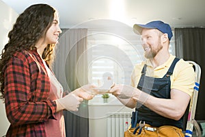 Hospitable lady giving coffee to repairman