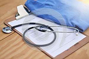 Hospital, clinic and stethoscope with clipboard on desk for medical service, medicine and notes. Healthcare, cardiology