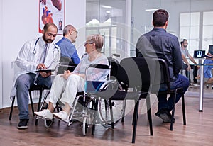 Hospital doctor in white coat communicating to senior woman in wheelchair x-ray