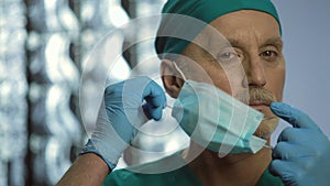 Hospital employee on duty taking off face mask, taking care of patients health