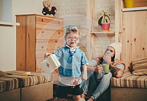 Hospital game, smiling boy dressed as doctor in red glasses holding first aid kit. Cute child with stethoscope playing