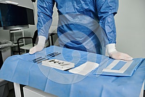 Hospital-gowned man preparing tools.