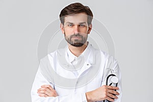 Hospital, healthcare workers, covid-19 treatment concept. Close-up of bearded serious-looking doctor in white scrubs