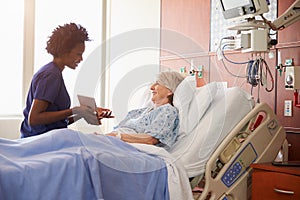 Hospital Nurse With Digital Tablet Talks To Senior Patient