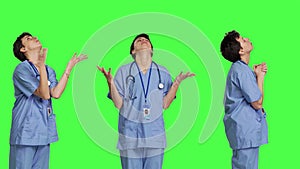 Hospital nurse worshipping God by prayer against greenscreen backdrop