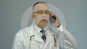 Hospital physician dialing number on smartphone, calling to consult patient