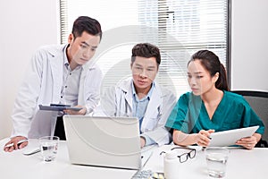 Hospital, profession, people and medicine concept - group of happy doctors with tablet pc computers meeting at medical office