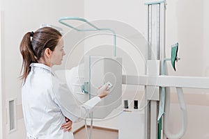 Hospital Radiology Room. Xray machine for fluorography. Doctor radiologist in gown adjusting the X-ray machine for
