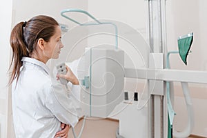 Hospital Radiology Room. Xray machine for fluorography. Doctor radiologist in gown adjusting the X-ray machine for