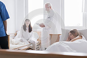 Hospital room with helpful doctors and ill patient