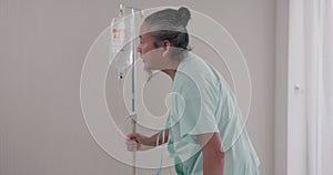 At the hospital, a senior man patient sits on a bed for a medical examination and walk recovery treatment for his disease. The