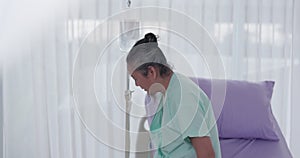 At the hospital, a senior man patient sits on a bed for a medical examination and walk recovery treatment for his disease. The