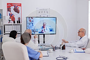 Hospital teamwork discussing with neurologist senior doctor during online videocall