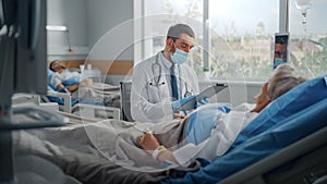 Hospital Ward: Friendly Doctor Wearing Face Mask Talks to Beautiful Senior Female Patient Resting in