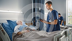 Hospital Ward: Friendly Male Nurse Talks with Elderly Patient Resting in Bed. Doctor Uses Tablet C
