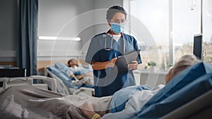 Hospital Ward: Friendly Nurse Wearing Face Mask Talks to Beautiful Senior Female Patient Resting in