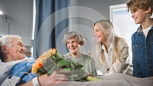 Hospital Ward: Grandfather Resting in Bed, His Caring Beautiful Grandmother Sitting Beside, Happy