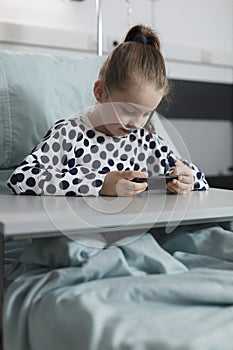 Hospitalized ill kid playing games on modern mobile phone