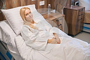 Hospitalized smiling lady lying in hospital bed