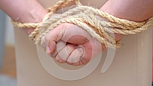 Hostage pulls hands tied behind back out of rope and frees