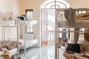 Real hostel`s interior. Hostel dormitory with bunk beds and sleeping travelers