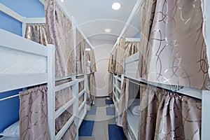 Hostel room. Empty bunk wooden beds with fabric curtains